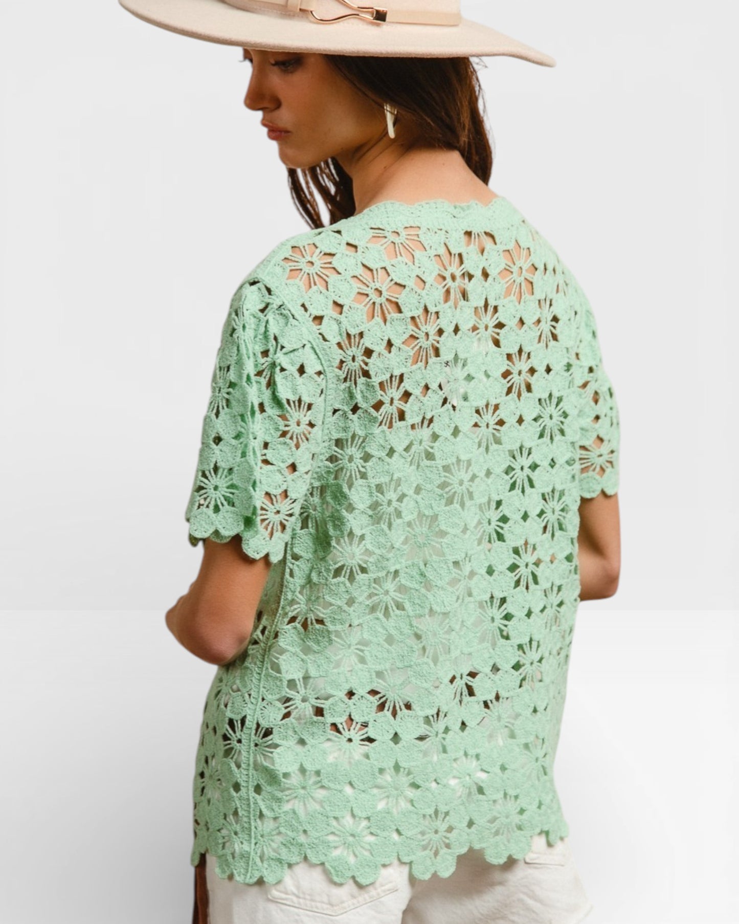 Woman wearing a light green lace top on a white background