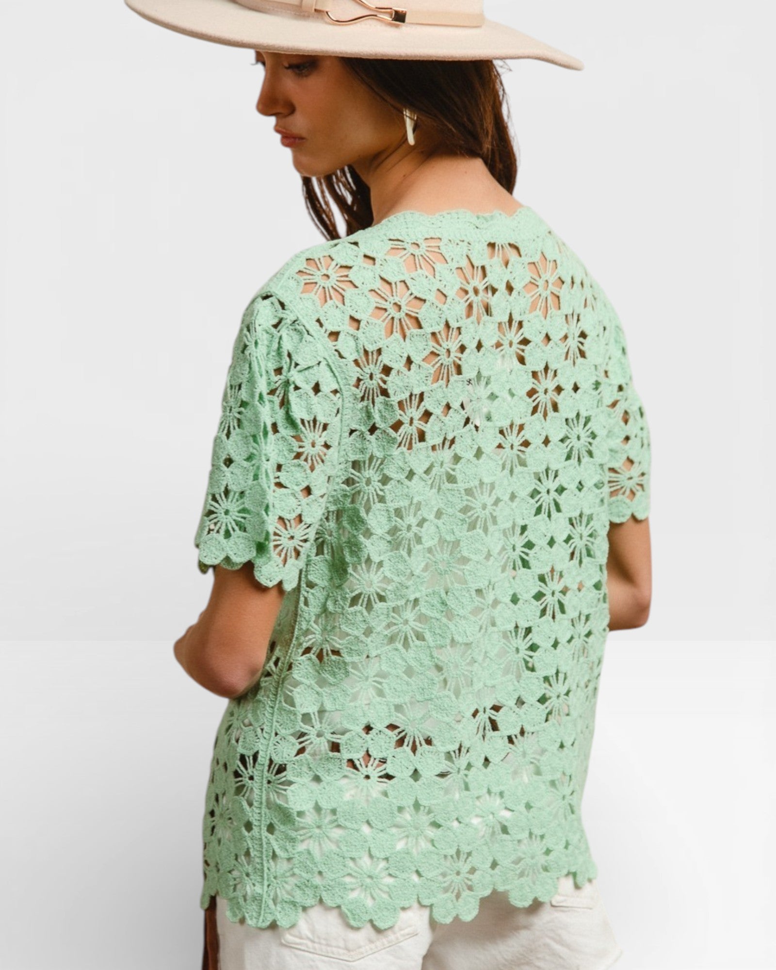 Woman wearing a light green lace top on a white background