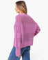 A woman wearing a lavender open-knit sweater and blue jeans, shown from a side-back angle against a plain white studio background.