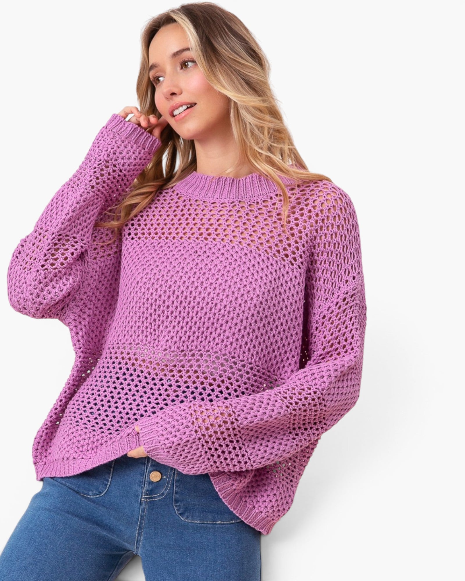 A woman wearing a lavender open-knit crewneck sweater and blue jeans, posing against a clean white background.