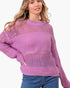 A woman wearing a lavender open-knit crewneck sweater and blue jeans, photographed against a plain light background.