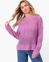 A woman wearing a lavender open-knit crewneck sweater and blue jeans, posing against a solid white studio background.