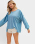 Woman wearing a blue oversized sweater with a pocket on a white background
