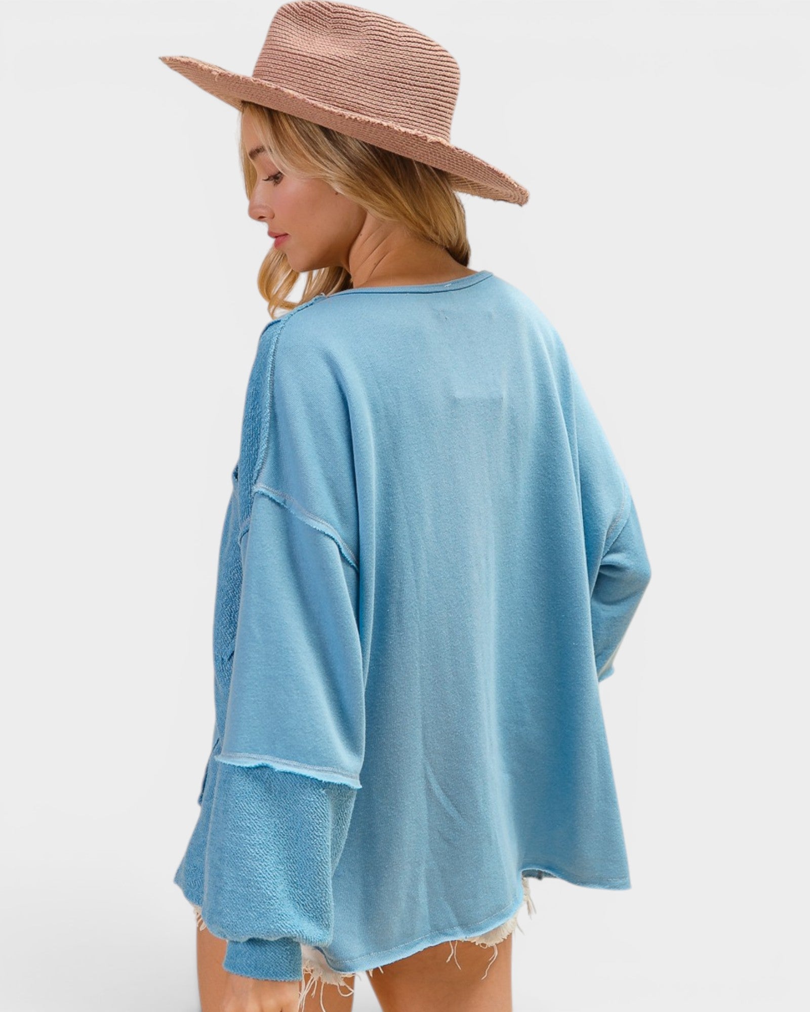Woman wearing a light blue kimono-style garment and a wide-brimmed hat on a white background