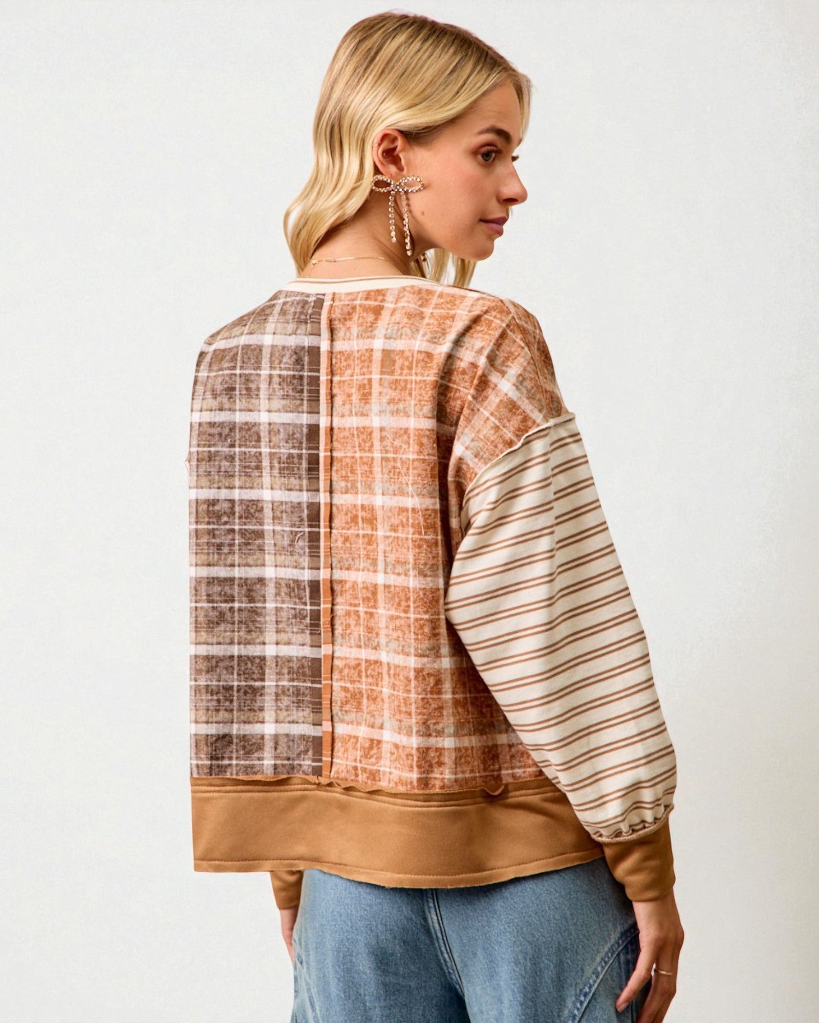 Woman wearing a plaid and striped long-sleeve top with a plain background