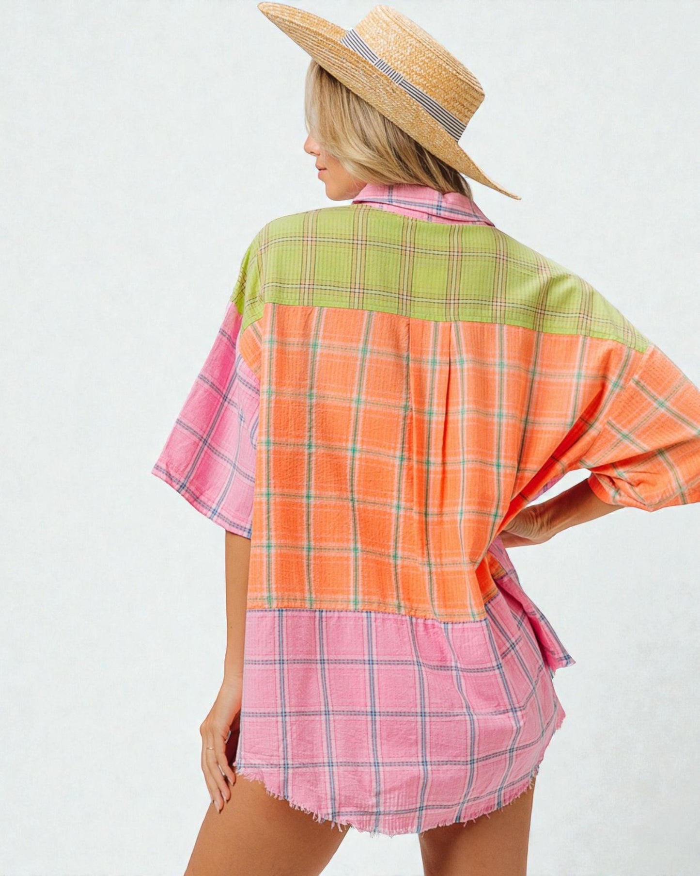 Woman wearing a colorful plaid shirt with a straw hat on a white background