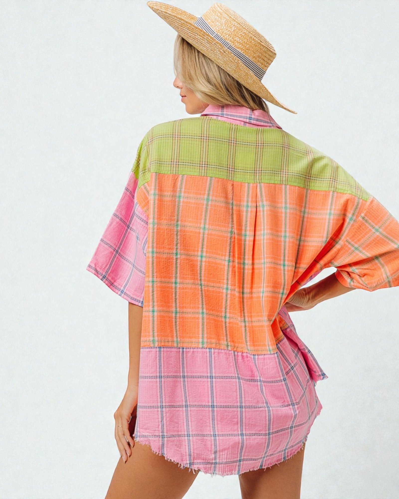 Woman wearing a colorful plaid shirt with a straw hat on a white background
