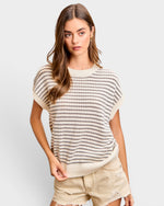 Woman wearing a striped sweater and shorts on a plain background