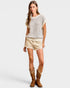 Woman wearing a striped shirt, beige shorts, and brown cowboy boots on a white background