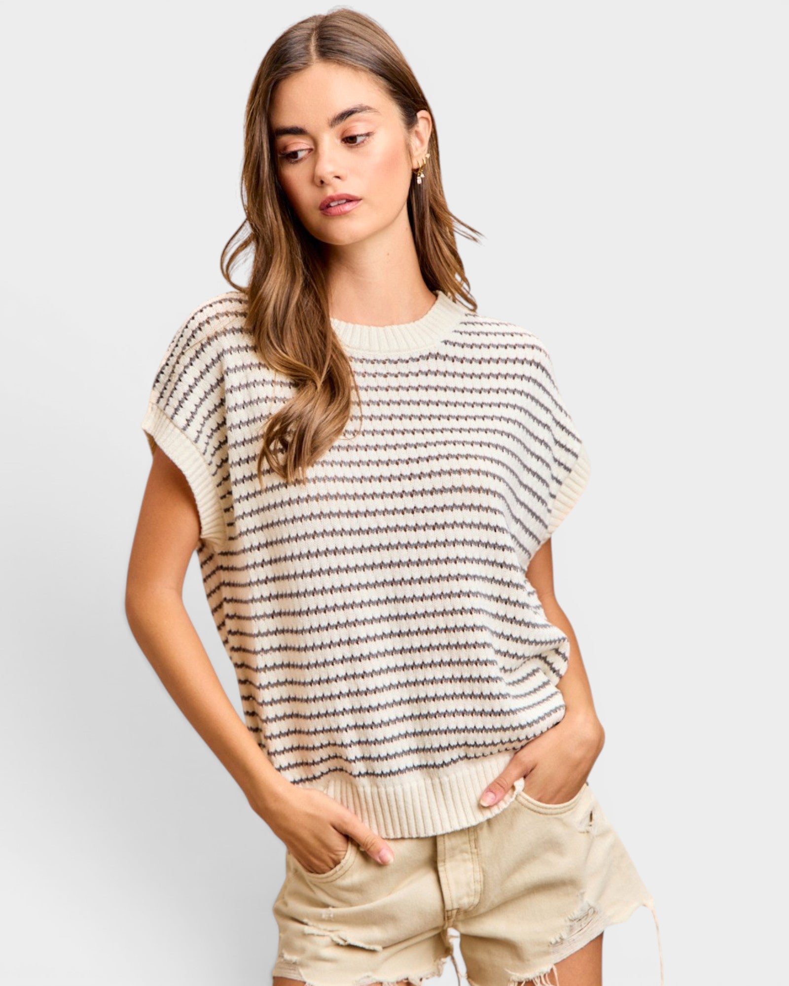 Woman wearing a striped sweater and shorts on a plain background