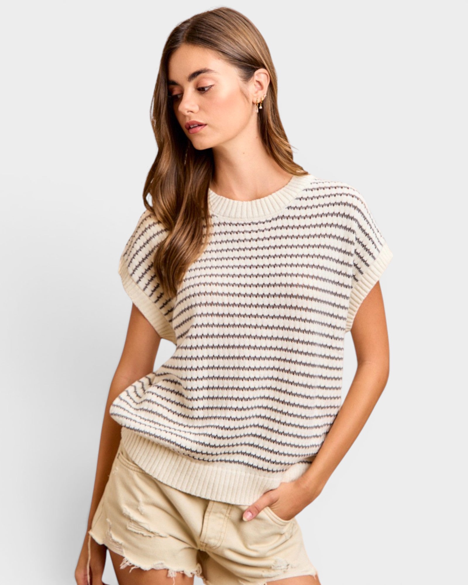 Woman wearing a striped sweater and shorts on a plain background