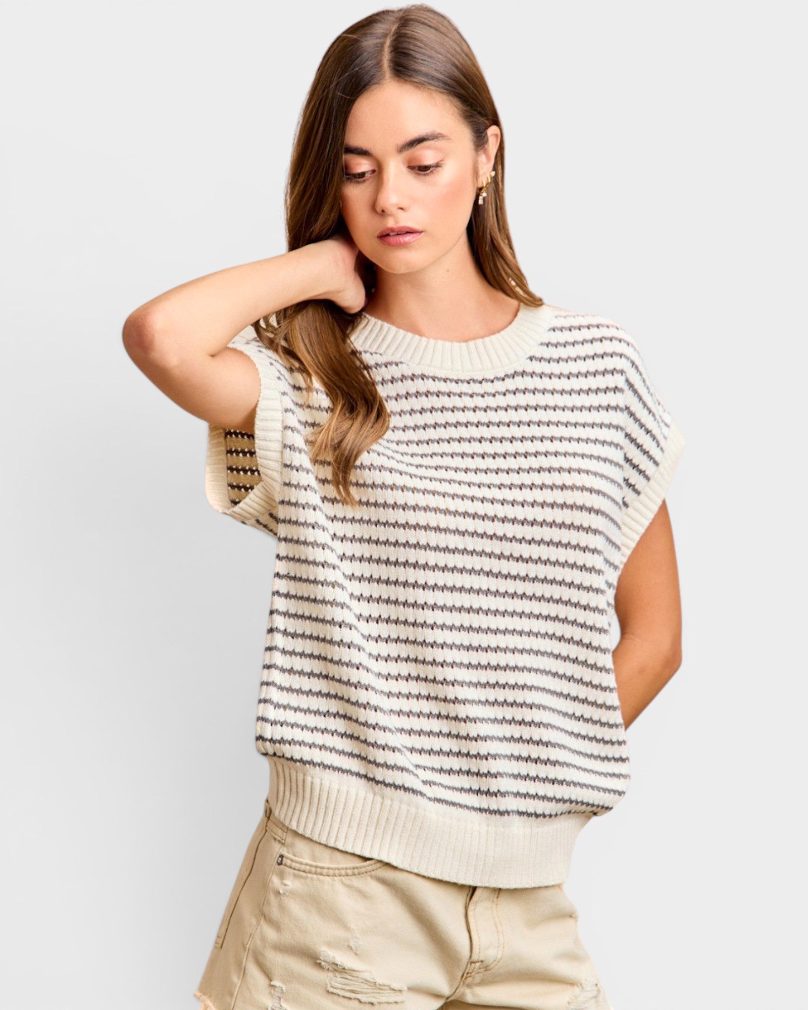 Woman wearing a striped sweater and beige pants on a light gray background