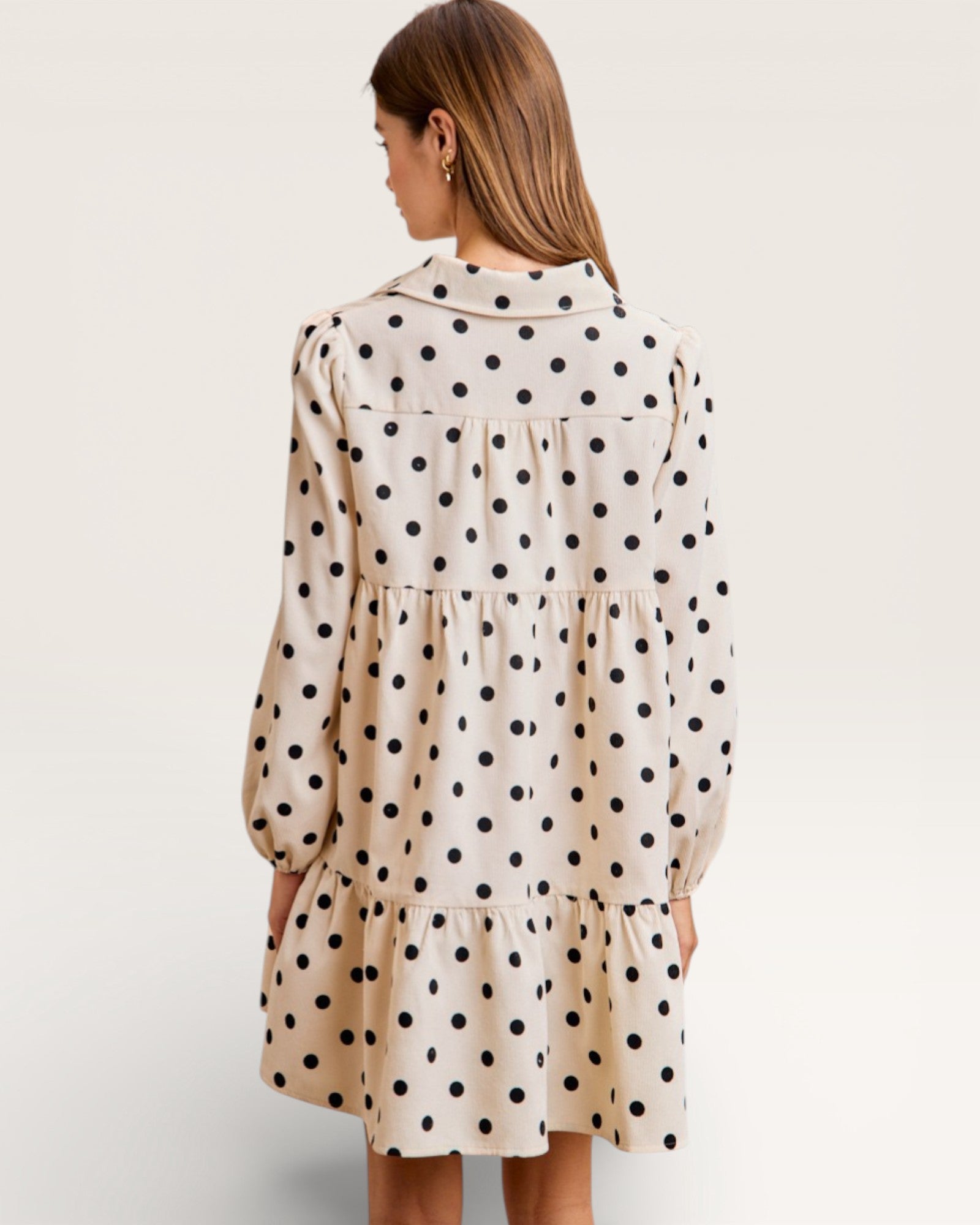 Woman wearing a polka dot dress on a plain background