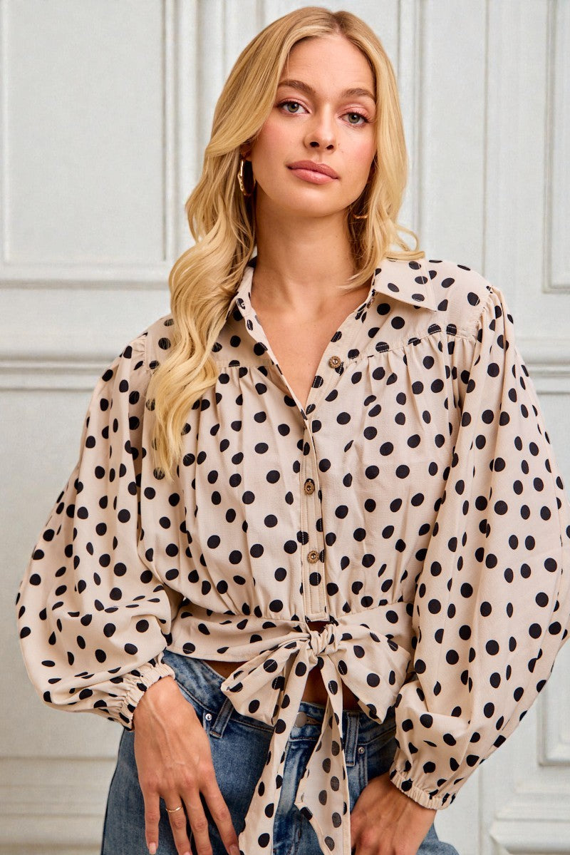Woman wearing a polka dot blouse with a neutral background
