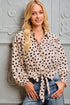 Woman wearing a polka dot blouse against a decorative wall.
