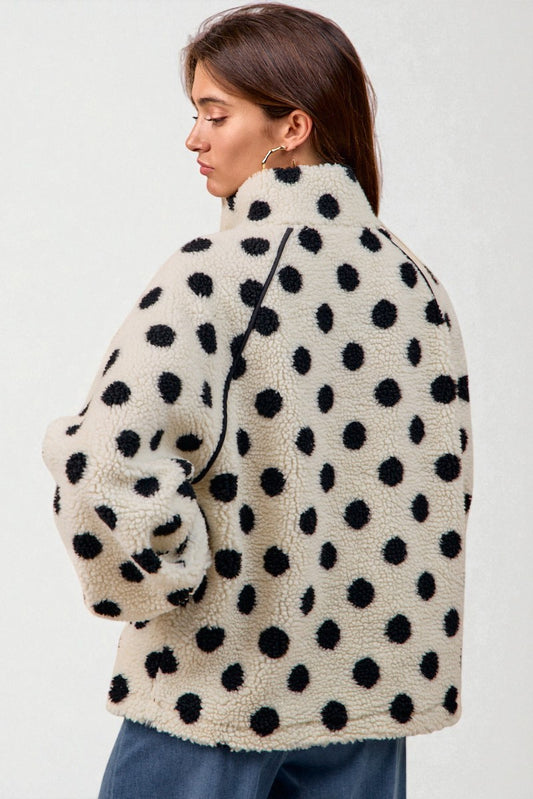 Person wearing a polka dot fleece jacket on a plain background