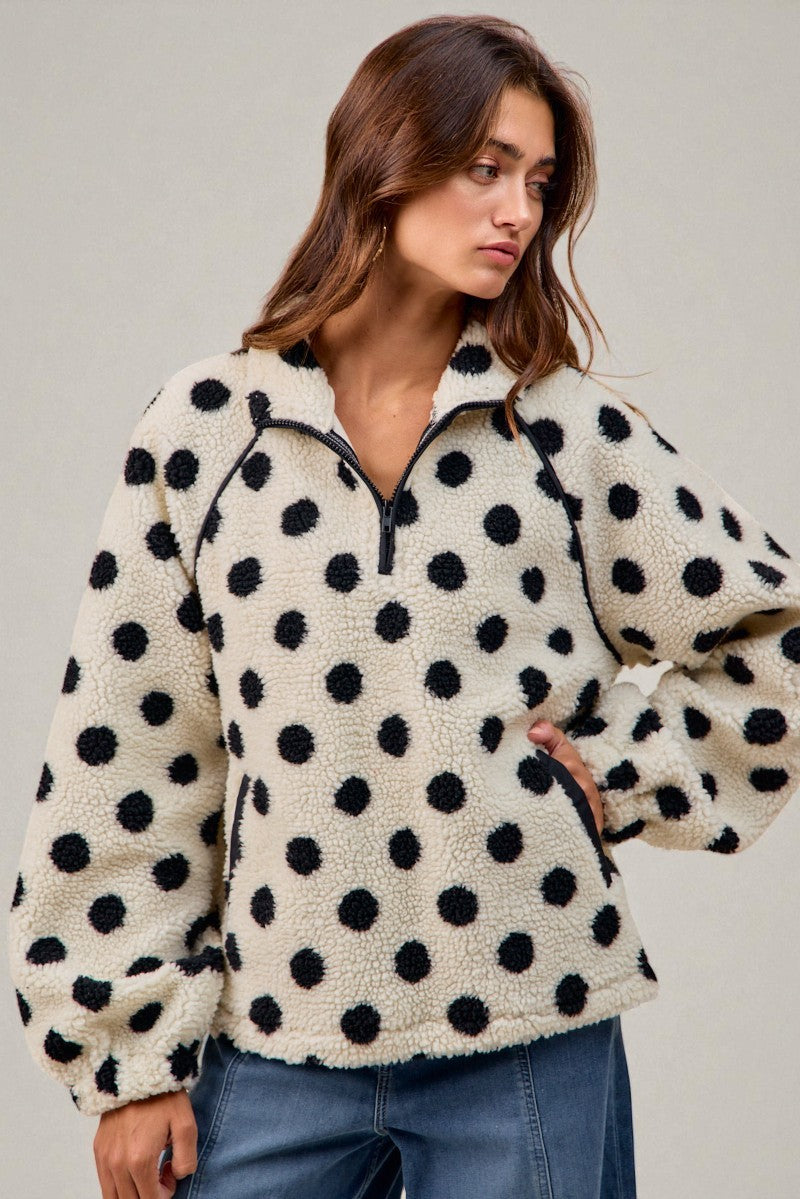 Woman wearing a polka dot fleece pullover against a plain background