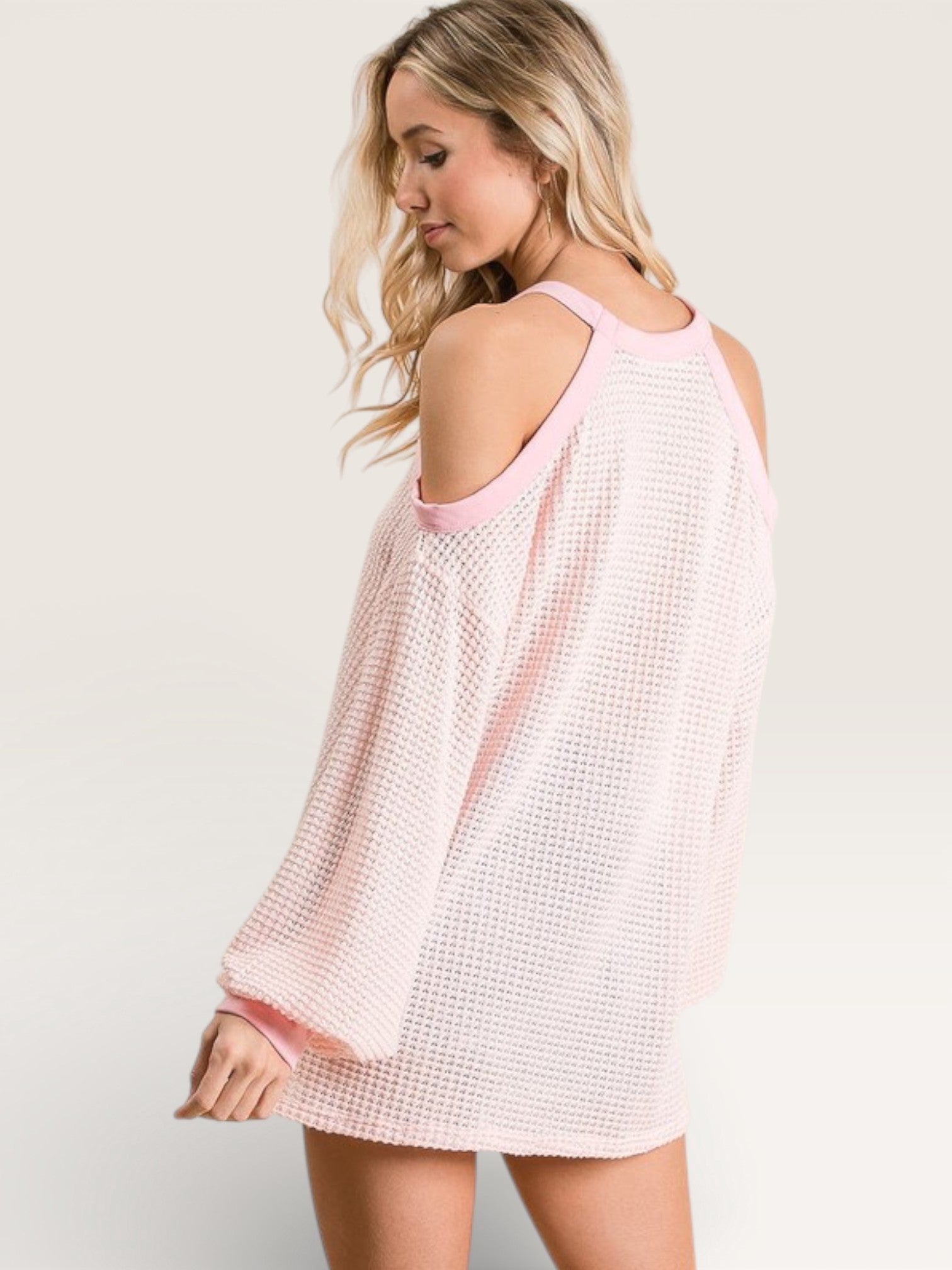 Woman wearing a light pink and white checkered dress on a plain background