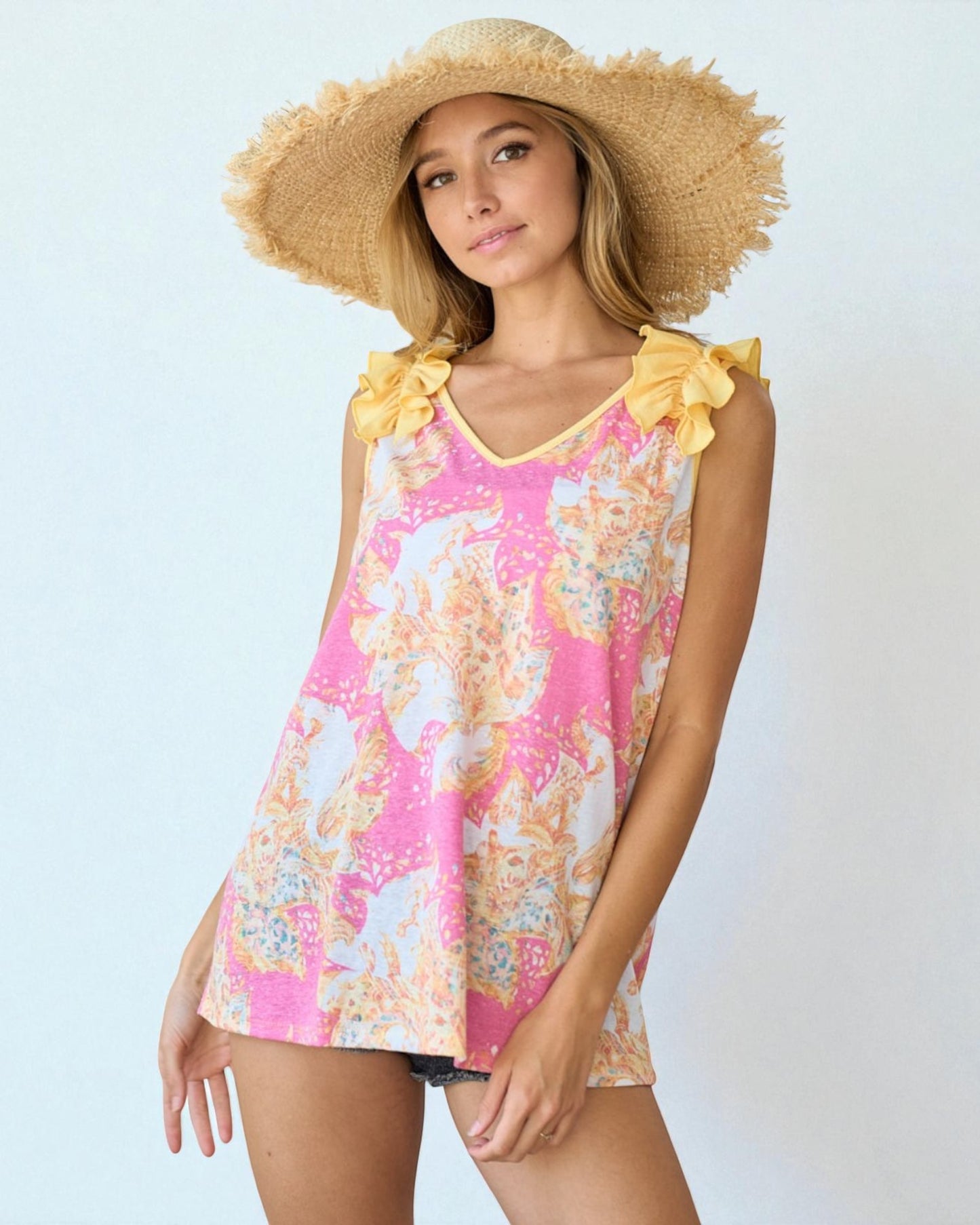 Woman wearing a floral tank top and straw hat on a light blue background
