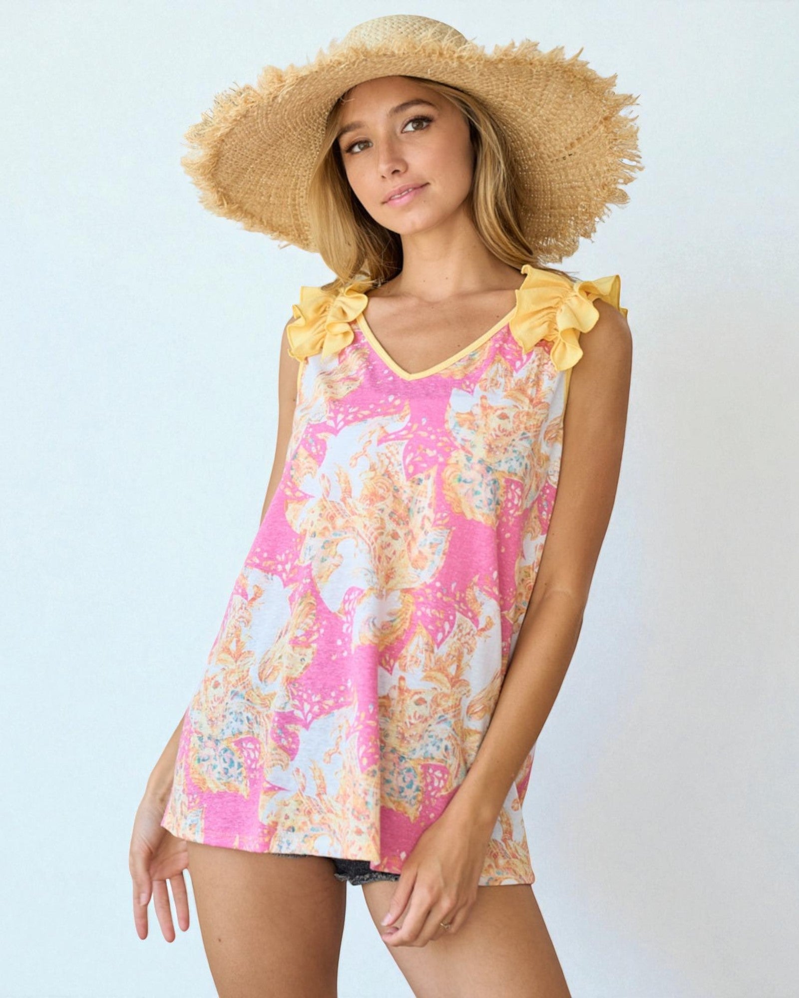 Woman wearing a floral tank top and straw hat on a light blue background