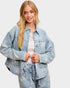 Woman wearing a light blue denim jacket on a white background