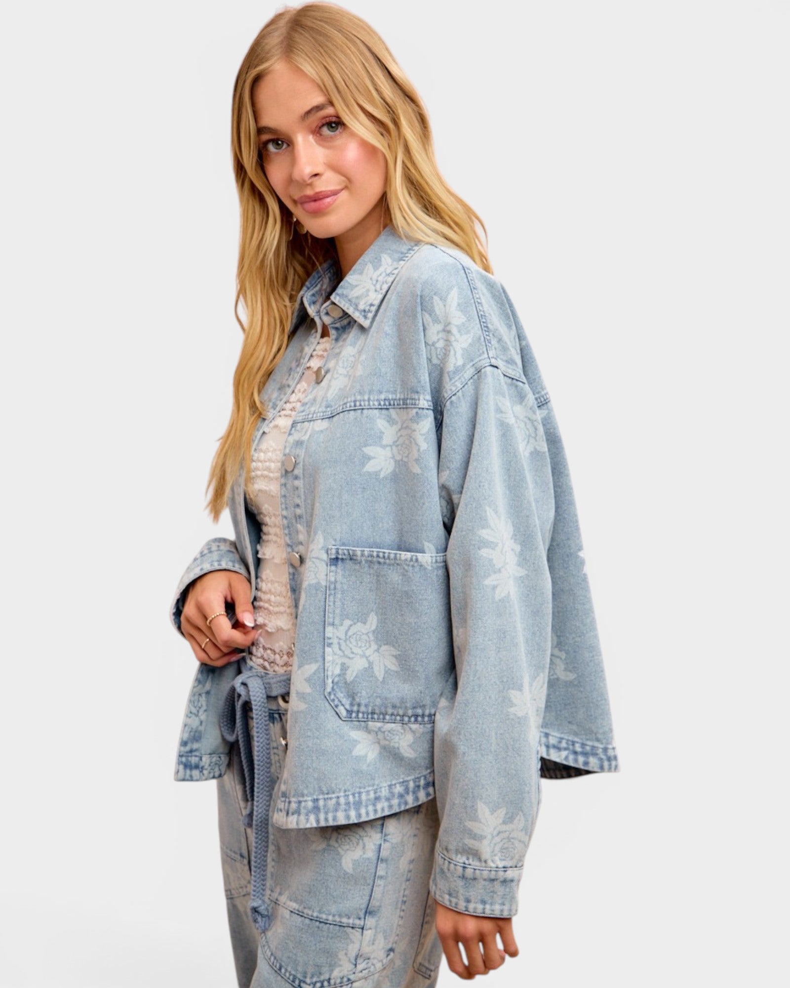 Woman wearing a light blue denim jacket with floral patterns on a white background