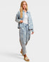 Woman wearing a light blue denim jacket and jeans on a white background
