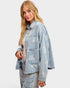 Woman wearing a light blue denim jacket with floral patterns on a white background