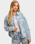 Woman wearing a light blue denim jacket on a plain background