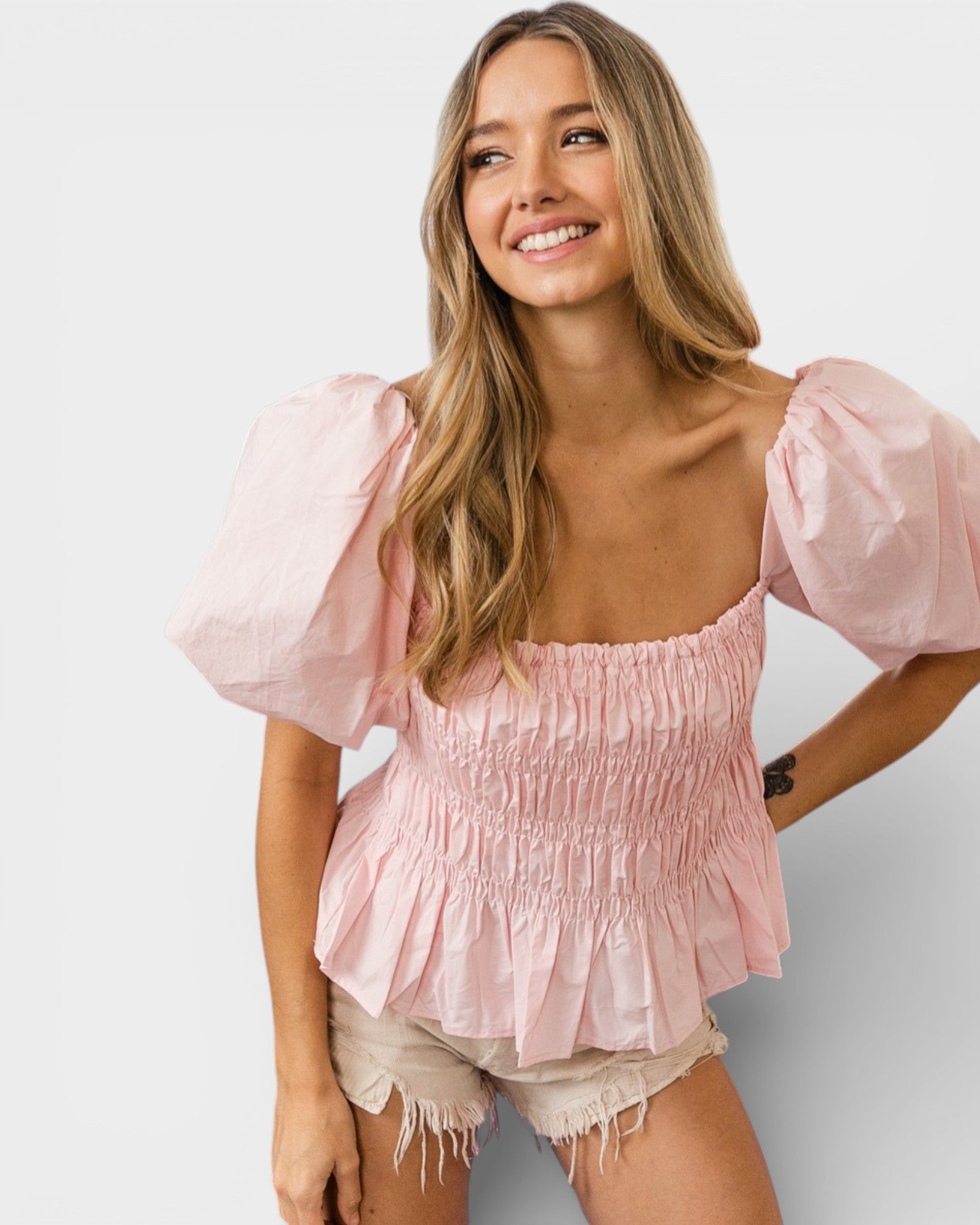 Woman wearing a pink blouse with puffed sleeves on a white background