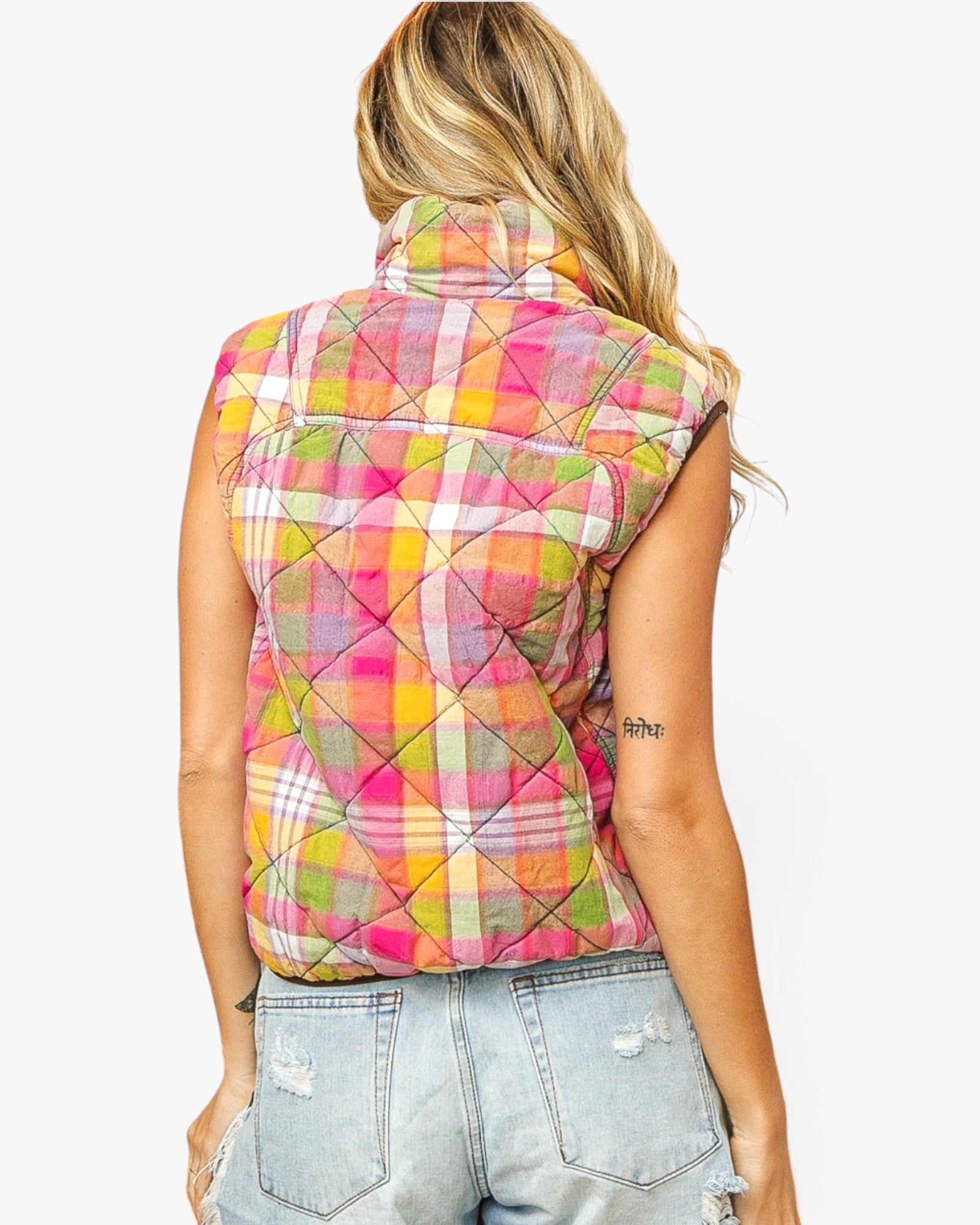 A woman shown from the back wearing a sleeveless quilted vest with a colorful plaid pattern in pink, yellow, green, and white, paired with light-wash distressed denim jeans against a plain white background.