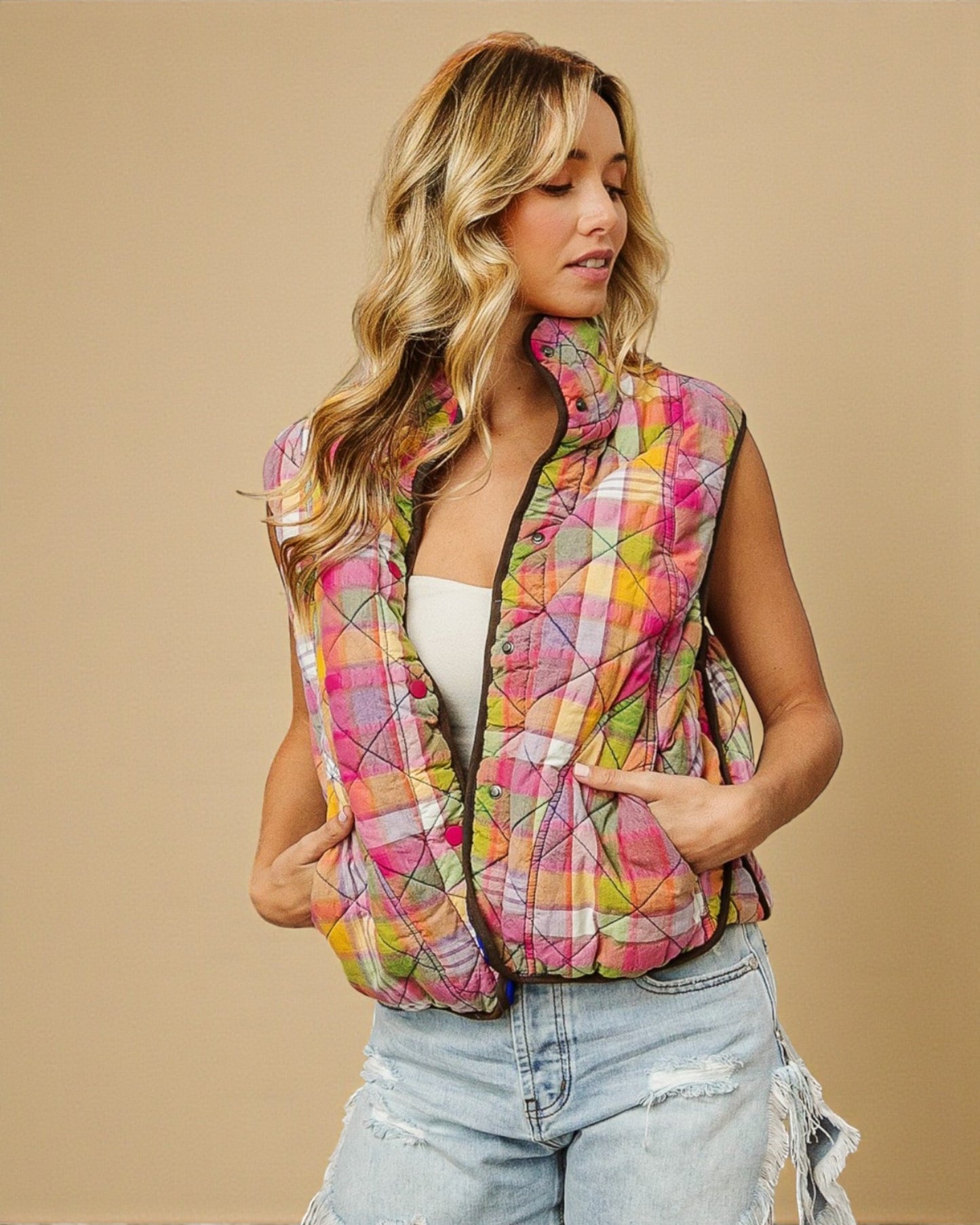 Woman wearing a colorful quilted vest against a beige background