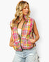 A woman wearing a sleeveless quilted puffer vest with a vibrant pink, orange, yellow, and green abstract plaid pattern, styled with light-wash distressed jeans against a plain white background.