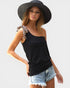 Woman wearing a black sleeveless top, denim shorts, and a wide-brimmed hat on a white background