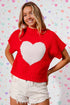 Woman wearing a red sweater with a white heart design against a heart-patterned background