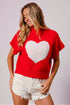 Woman wearing a red sweater with a white heart design on a plain background
