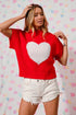 Woman wearing a red sweater with a white heart design against a colorful heart-patterned background