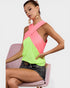 Woman wearing a pink and green top sitting on a pink chair with a white background