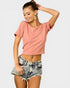 Woman wearing a pink crop top and denim shorts on a light gray background
