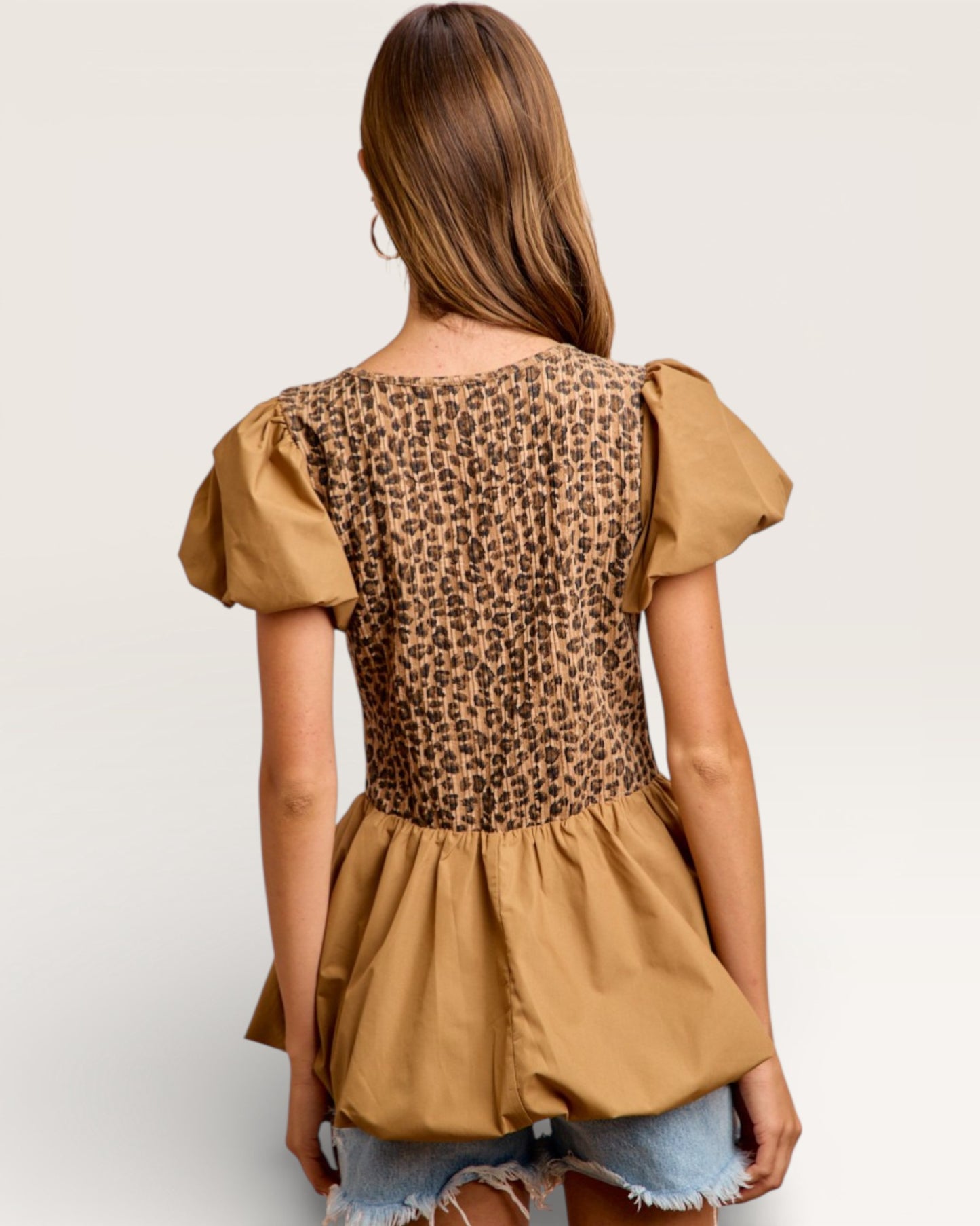 Woman wearing a leopard print top with beige sleeves and bottom on a white background