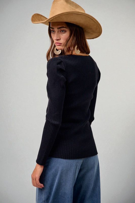 Woman wearing a black sweater and beige hat on a plain background