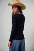 Woman wearing a black sweater and beige hat on a plain background