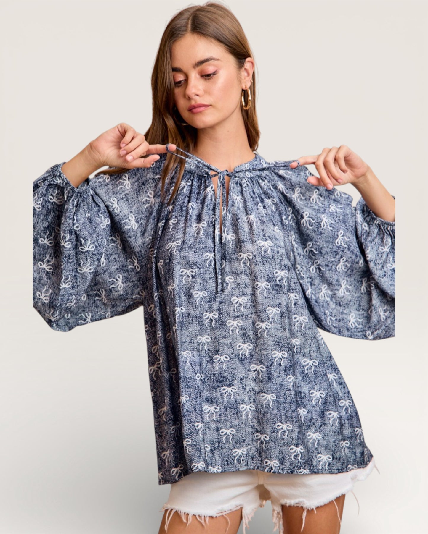 Woman wearing a blue patterned blouse with balloon sleeves on a plain background