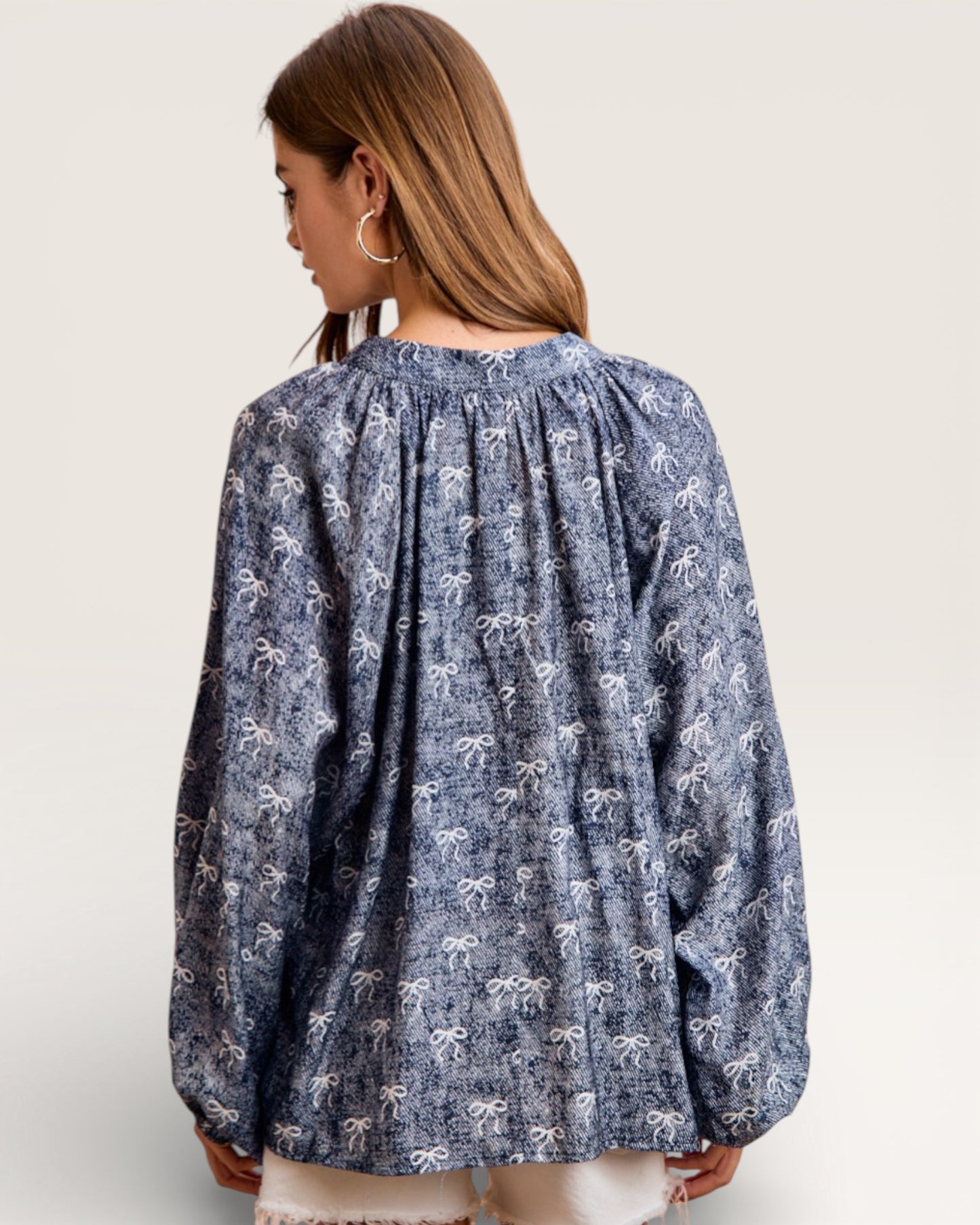 Woman wearing a blue patterned blouse on a plain background