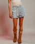 Person wearing a patterned skirt and brown cowboy boots on a plain background