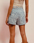 Person wearing blue shorts with a subtle pattern on a plain background