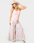 Woman wearing a pink sleeveless top and floral wide-leg pants on a white background