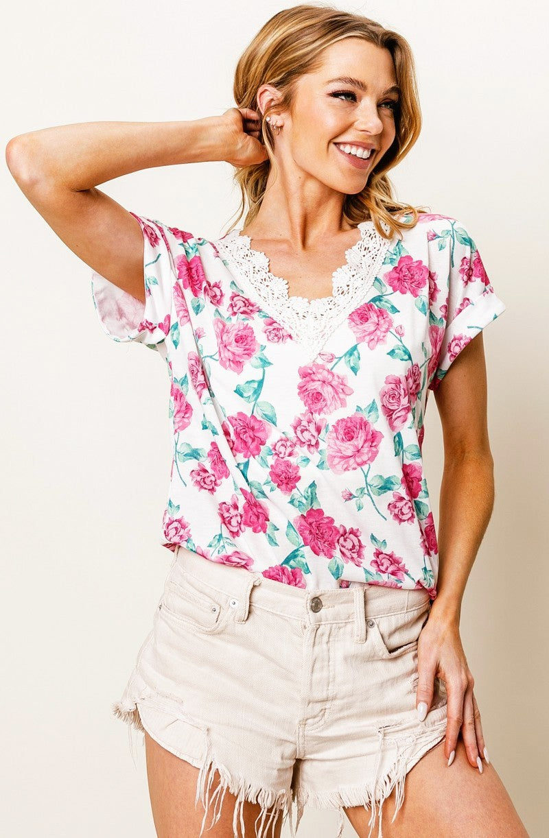 Woman wearing a floral top and shorts against a plain background