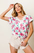Woman wearing a floral top and shorts against a plain background