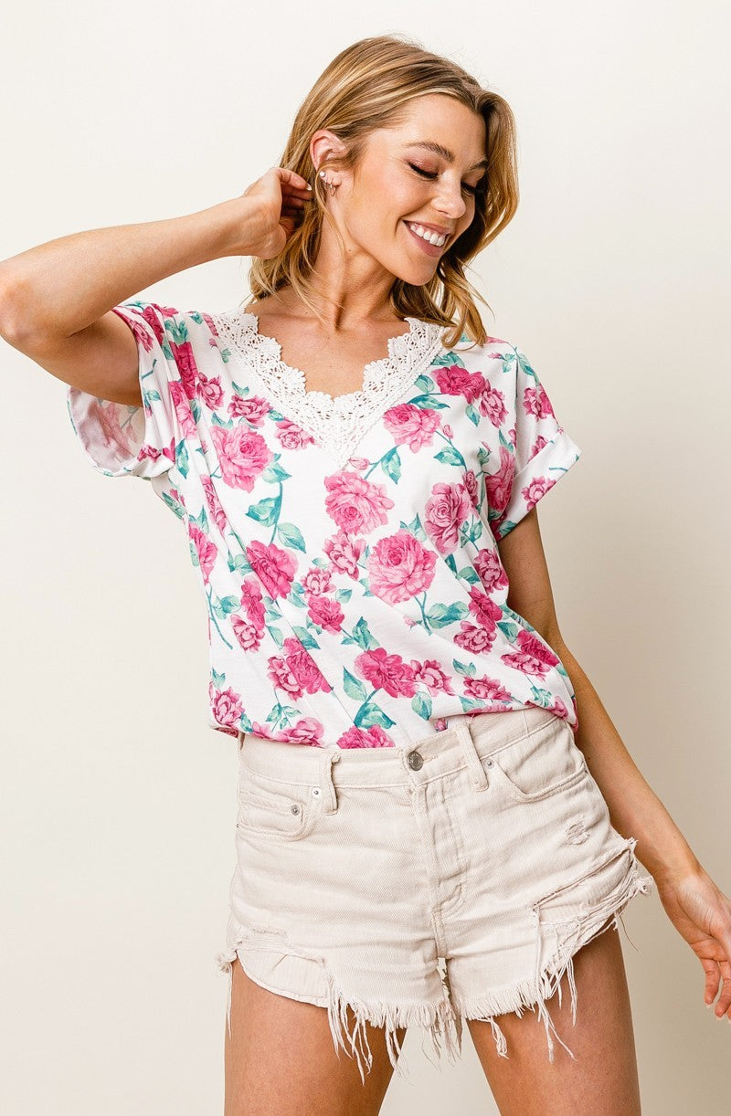 Woman wearing a floral top and denim shorts against a plain background
